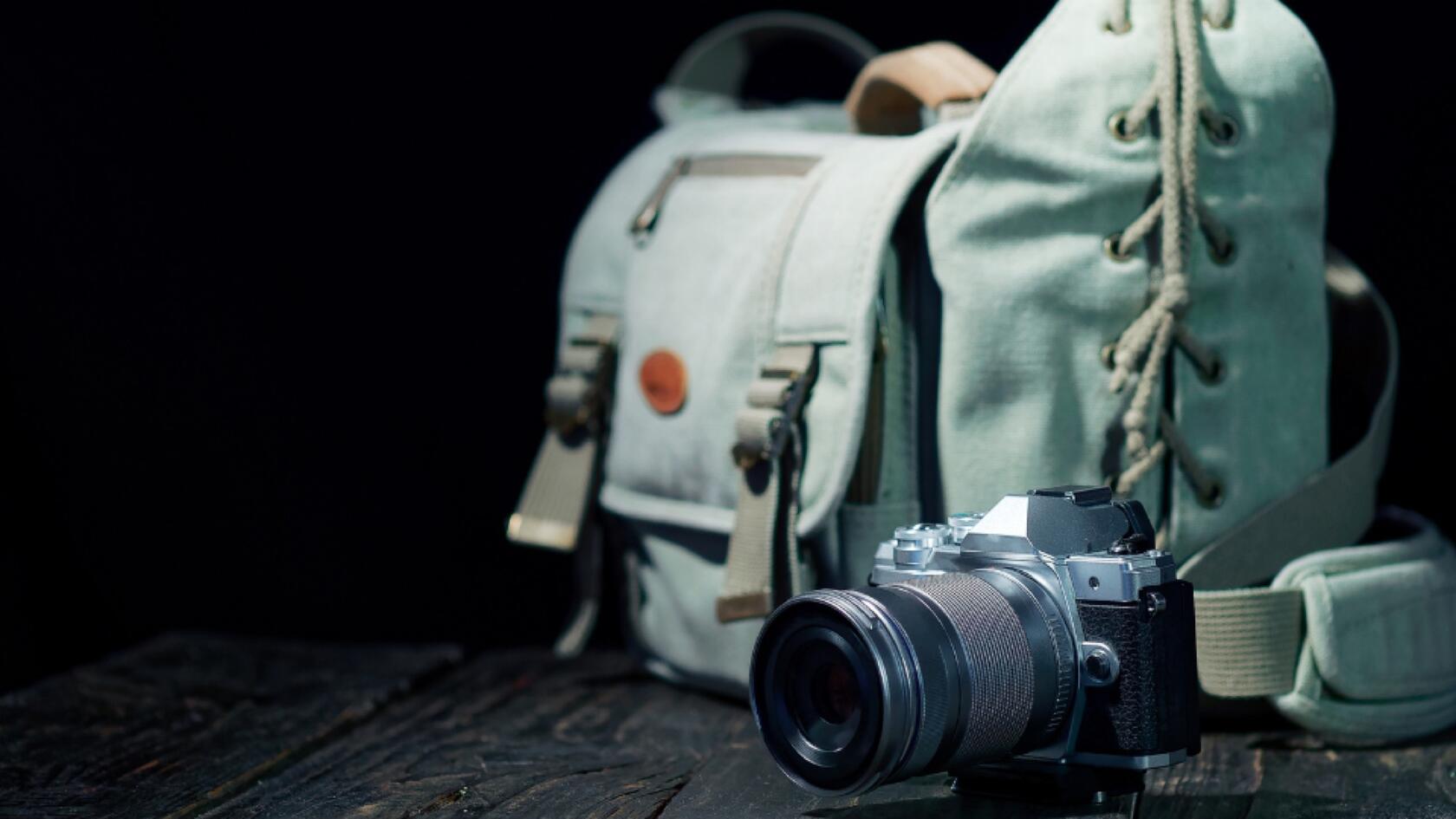 A camera sits in front of a camera bag