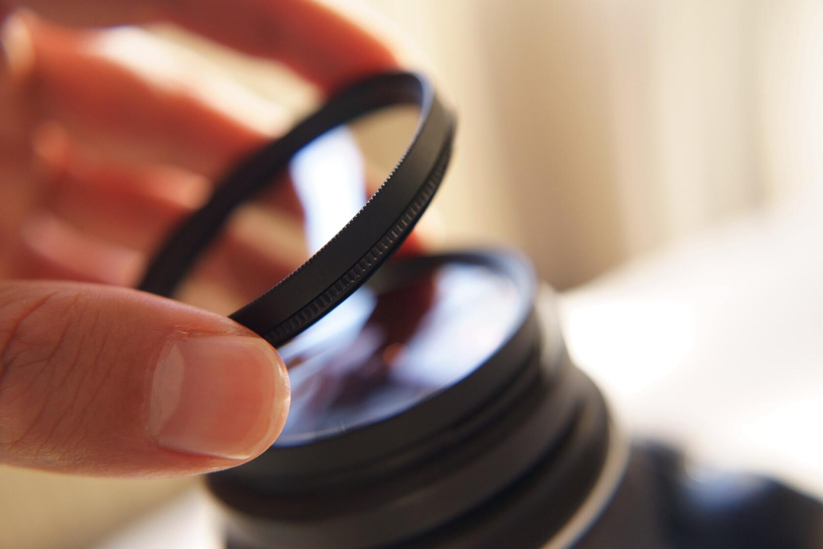 A person changing filters on a camera lens