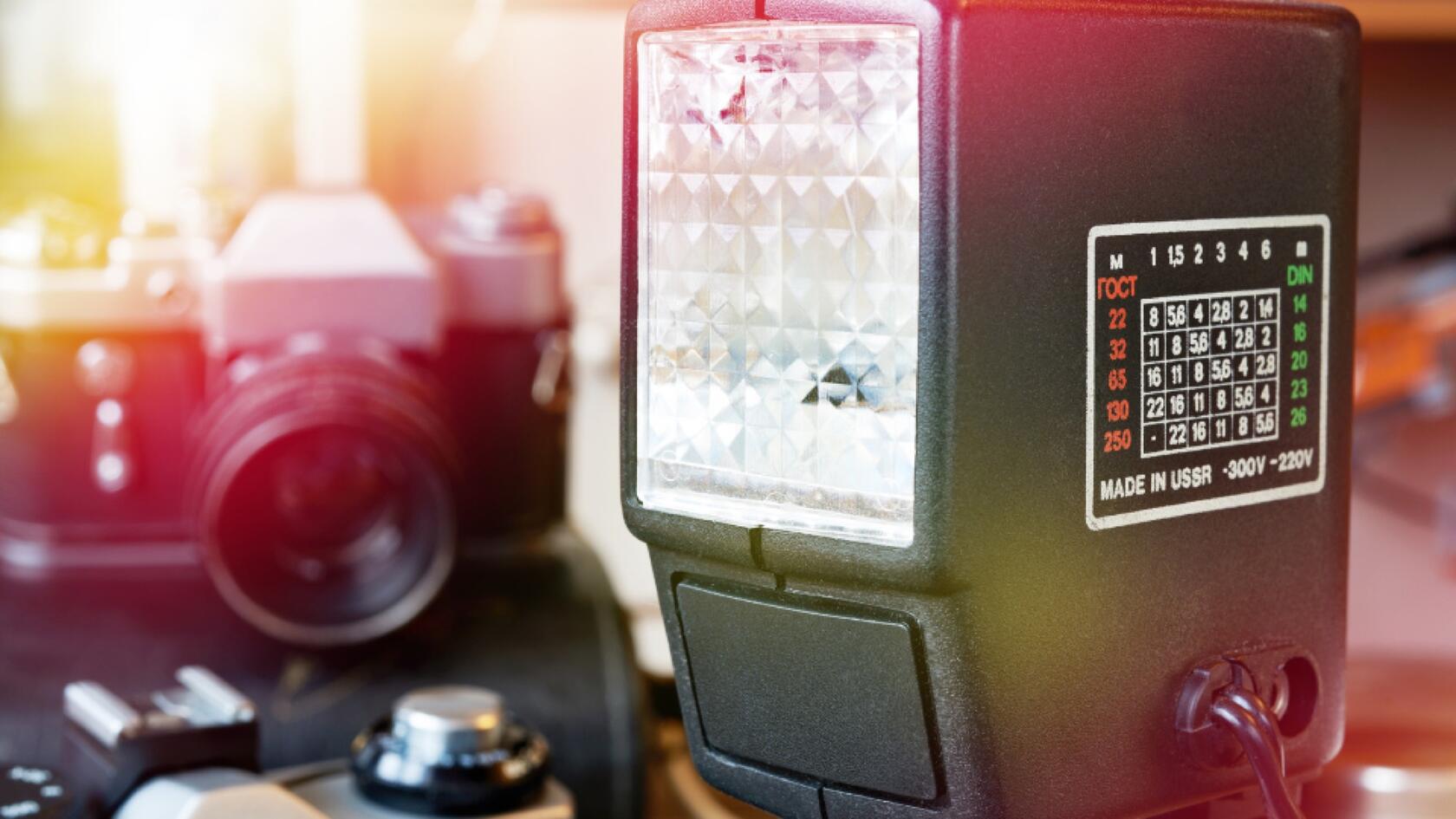 A photo camera with a flashlight in the foreground