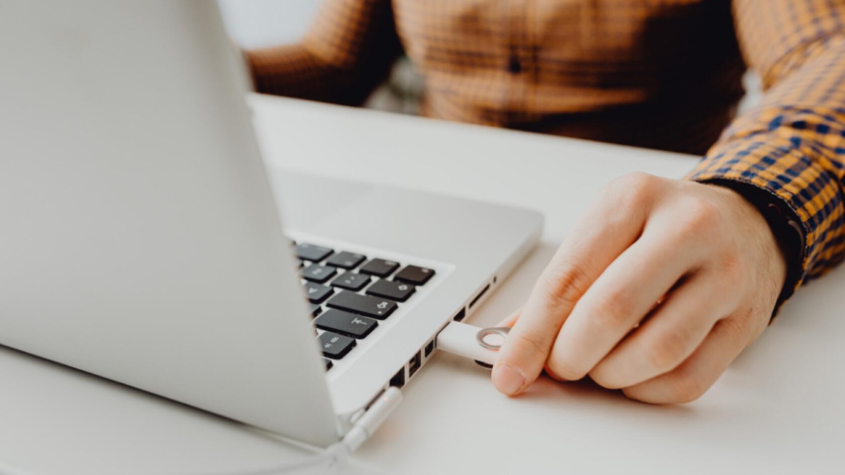 A person plugs a USB drive into a laptop computer