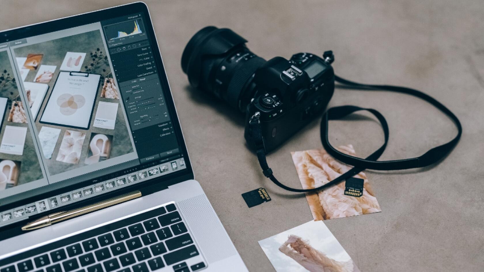 A laptop, a camera, photographs and memory cards on a table