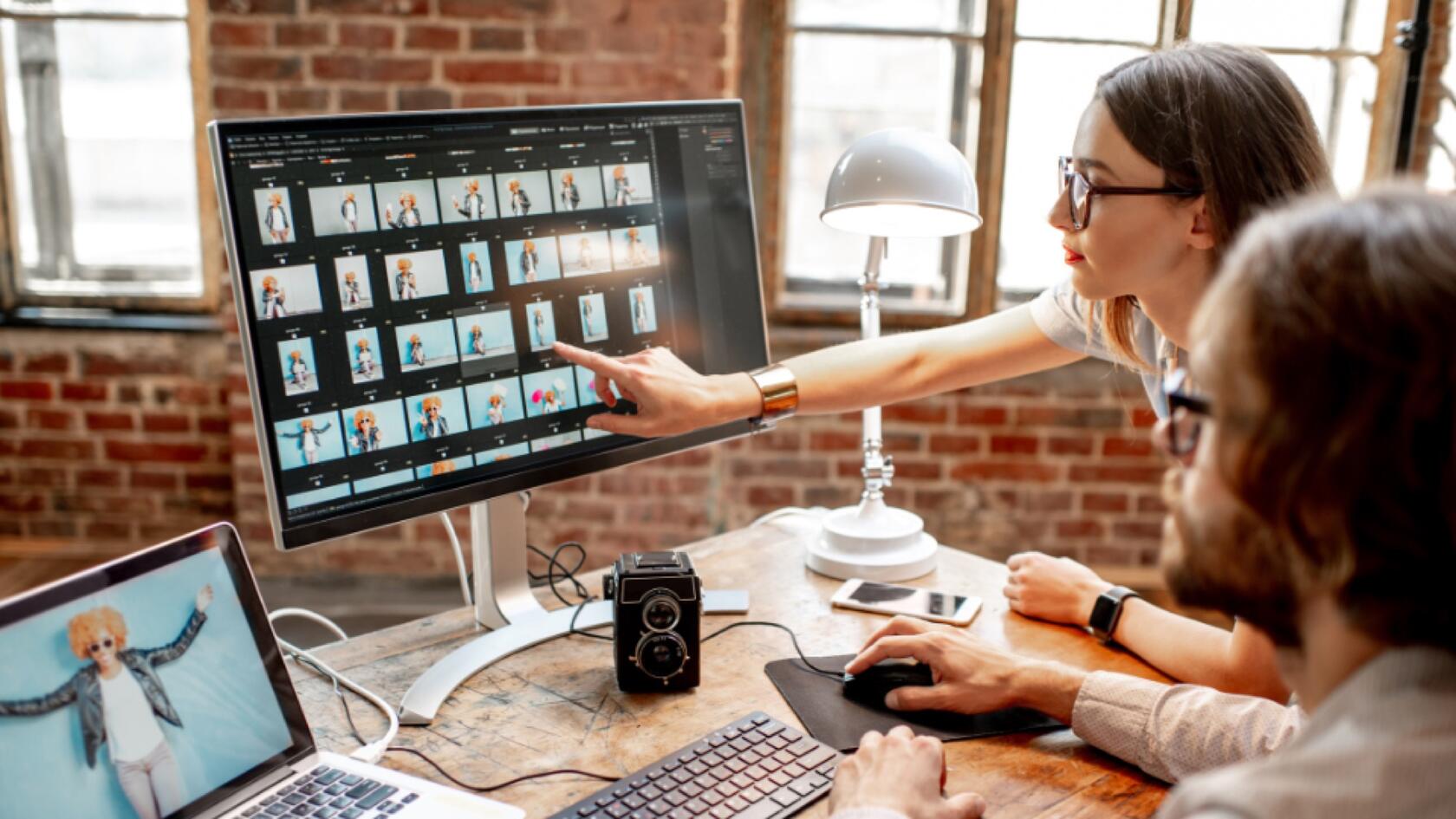 Two people selecting images from a photo shoot at a computer screen