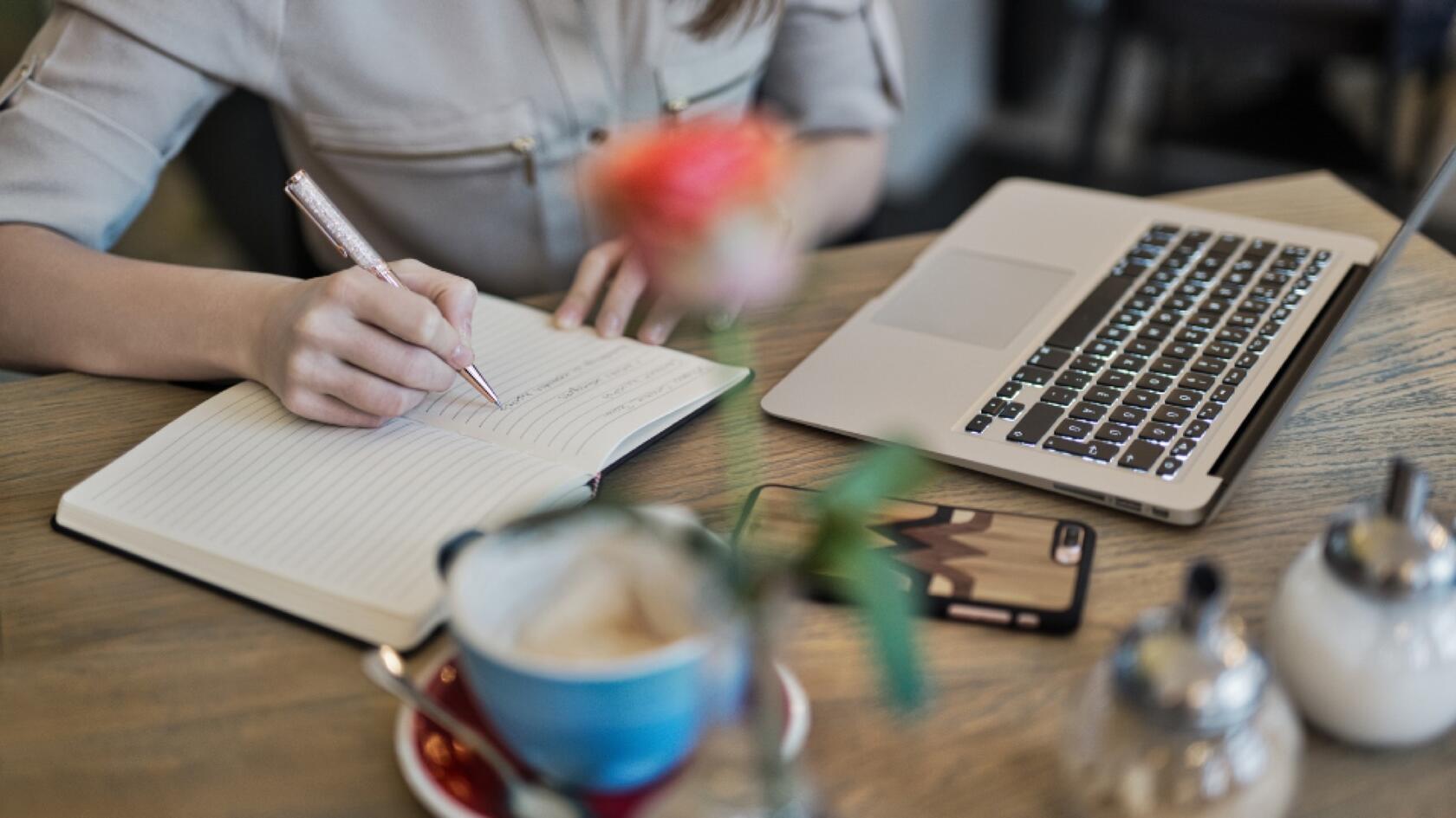 a person sitting at a desk writing in a notebook