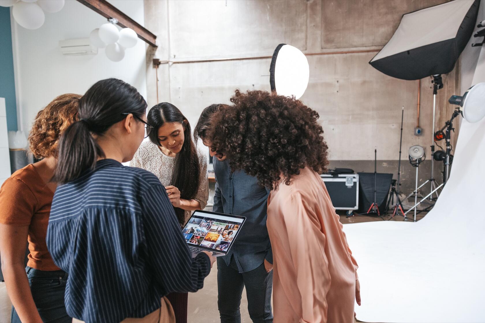 five persons looking a photographs on a screen in a photo studio