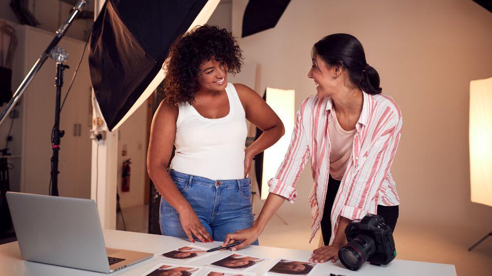  a photographer and client in a photo studio looking at pictures