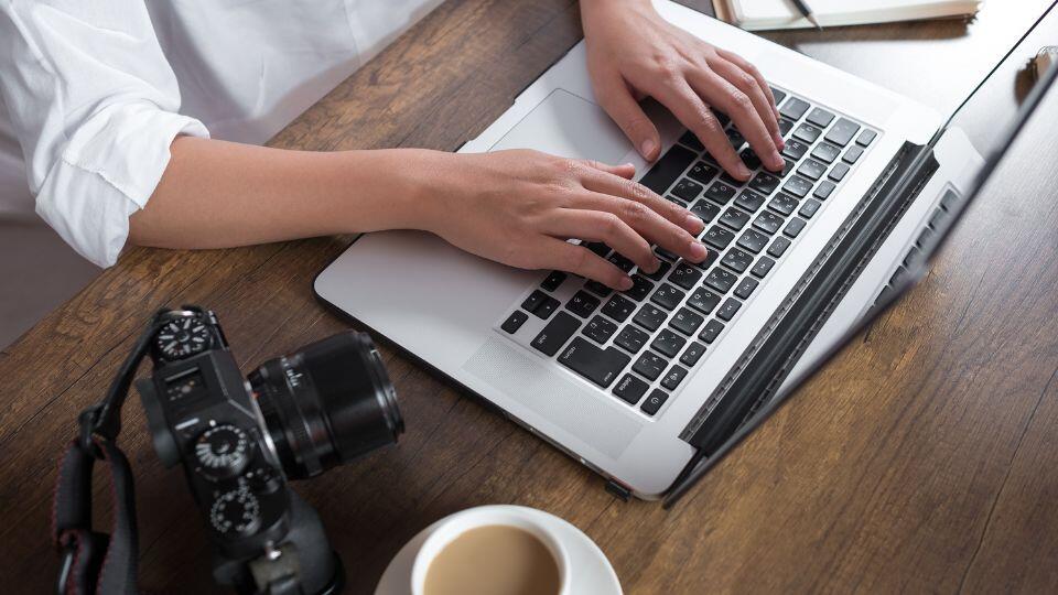 A person sitting at a desk with a laptop and camera