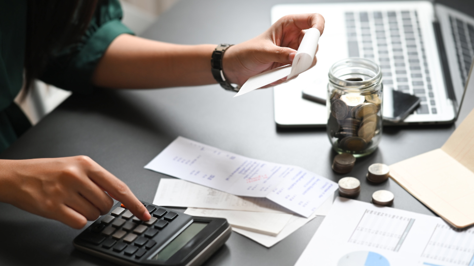 A person sitting on a desk, checking receipts and bills