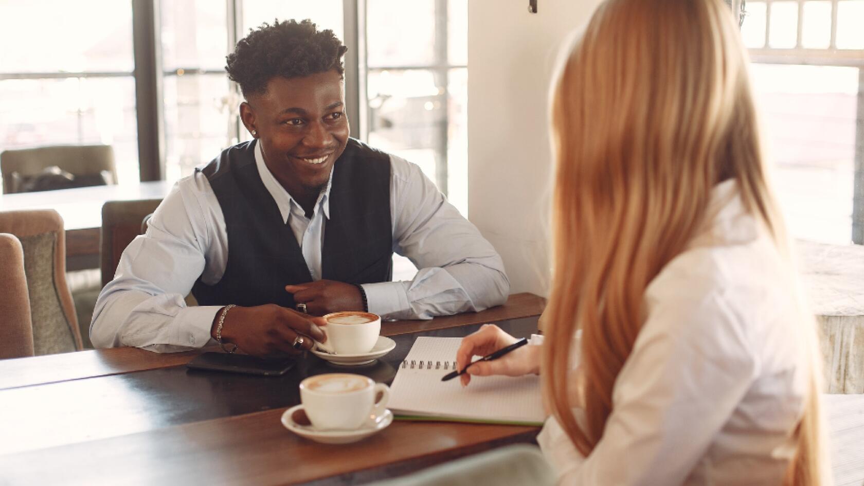 Two people sitting at a table with a cup of coffee