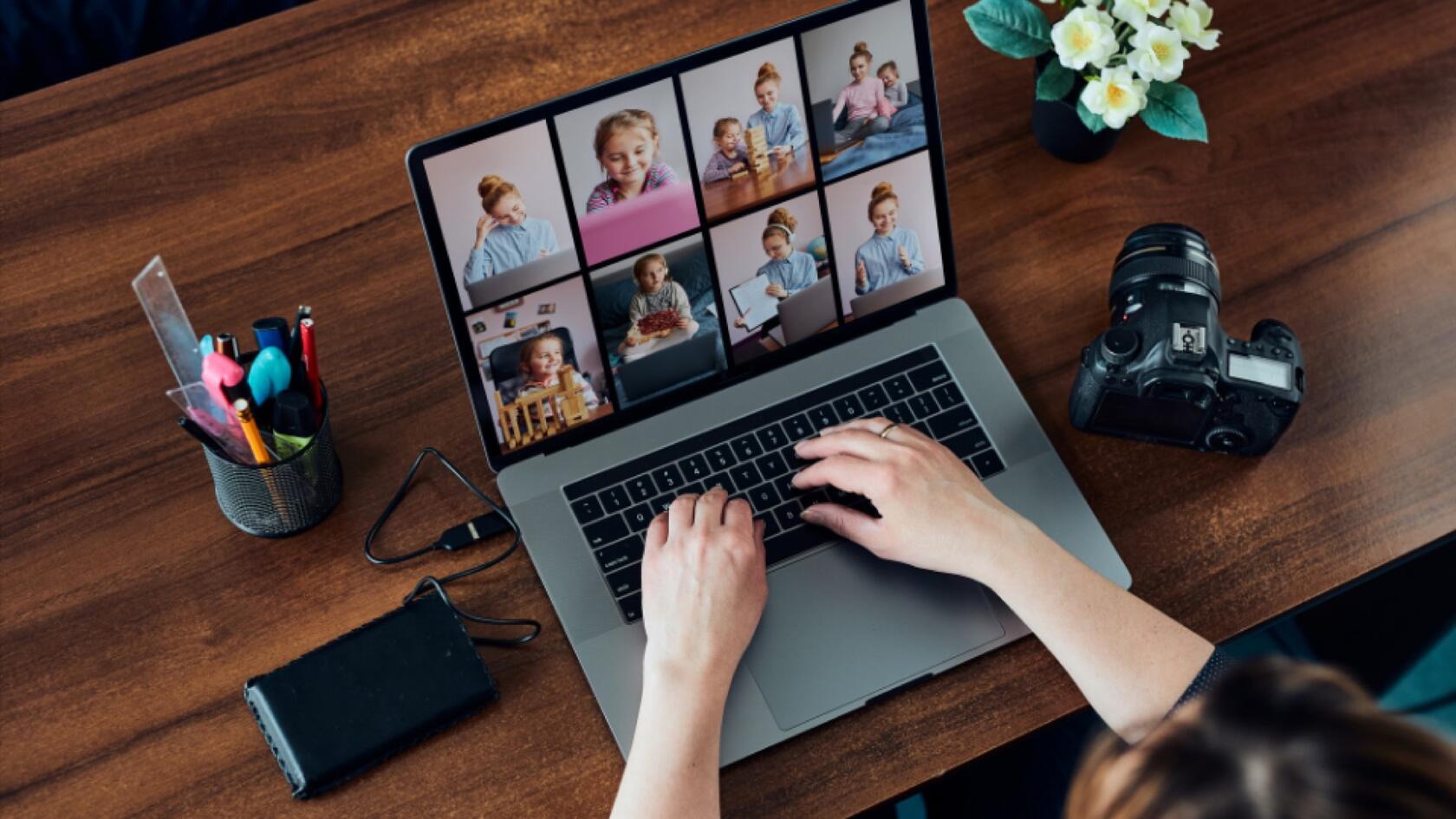 A person typing on a laptop with photos on the screen