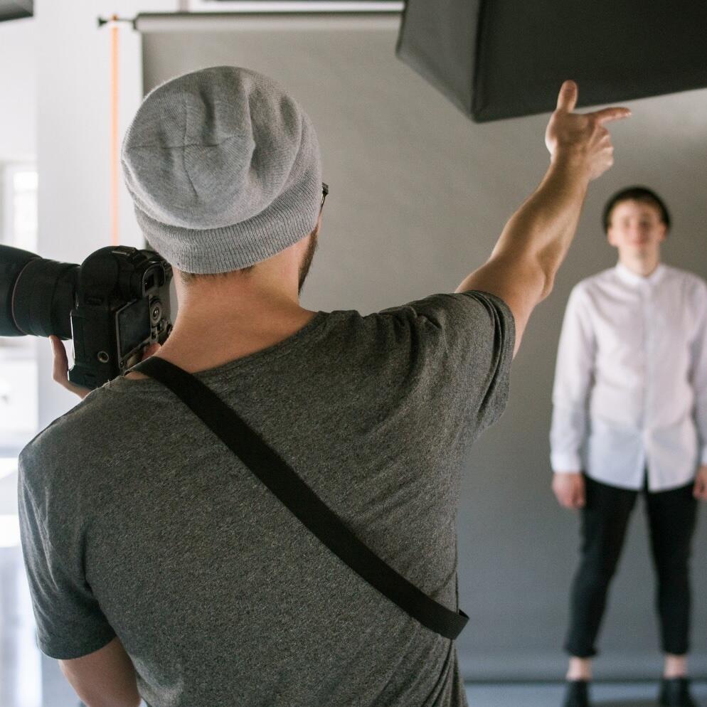 A photographer in a photo studio, taking portrait photographs and giving instructions