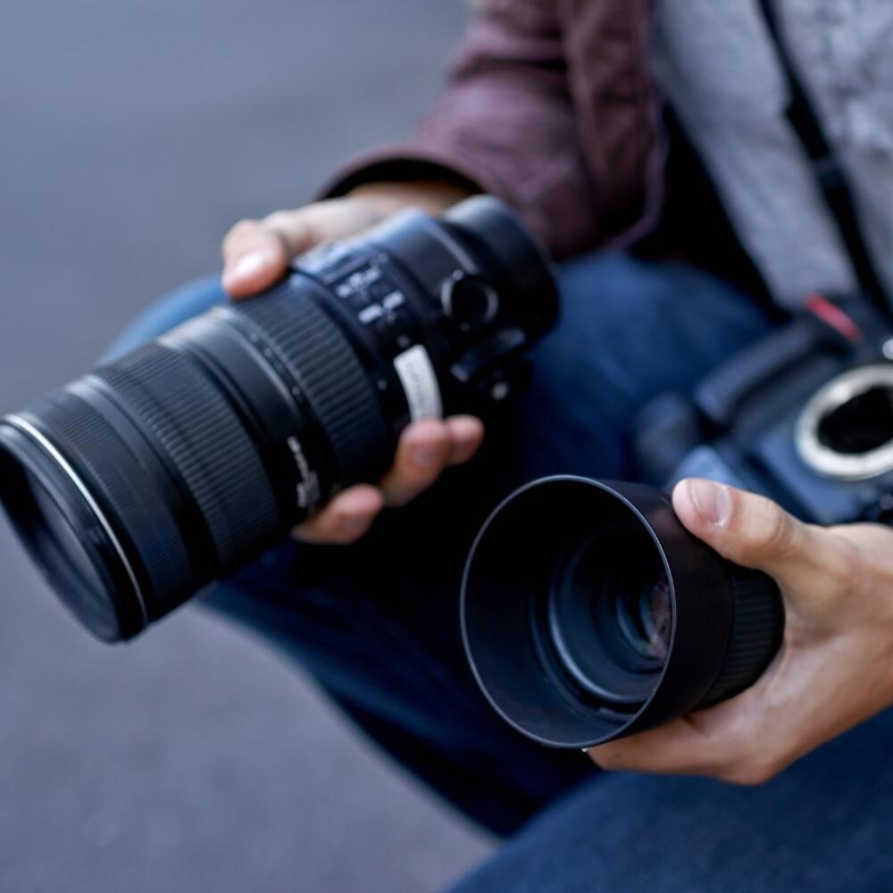 A person holding two camera lenses
